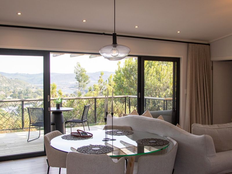 Open plan living area featuring large sliding glass doors that open onto a timber deck with scenic landscape views.