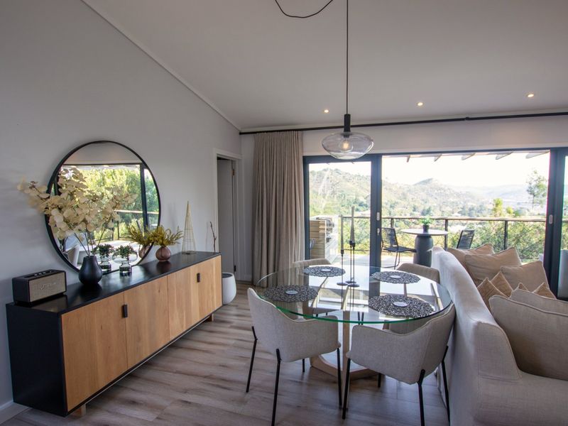 Modern open-plan living and dining area featuring laminate flooring, recessed lighting, and large sliding doors opening to a scenic balcony.