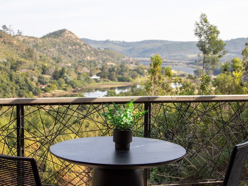 A balcony featuring a decorative metal balustrade with scenic views of the surrounding hills, river, and natural landscape.