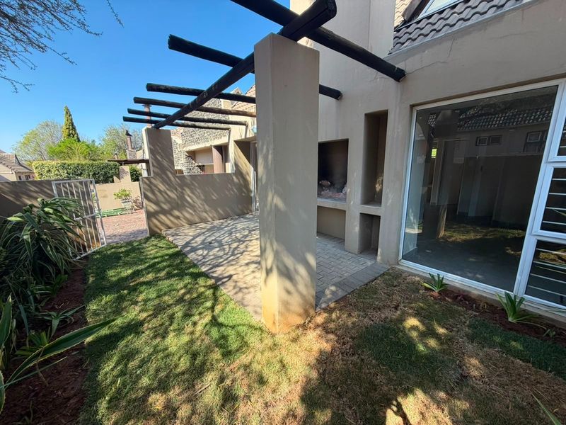 Outdoor patio area featuring a built-in braai, timber pergola, and paved flooring, providing a functional space for outdoor entertaining.