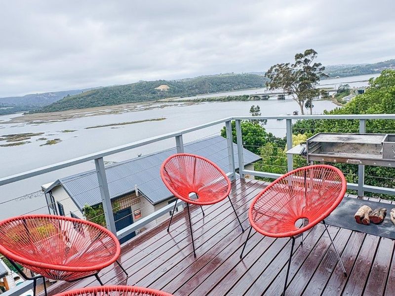 An elevated timber balcony featuring a built-in barbecue and expansive views over the surrounding estuary and landscape.