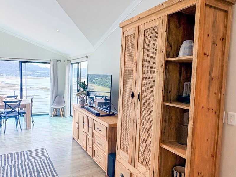 Bright open-plan living area featuring vaulted ceilings, recessed lighting, and large sliding glass doors that provide expansive views and natural light.