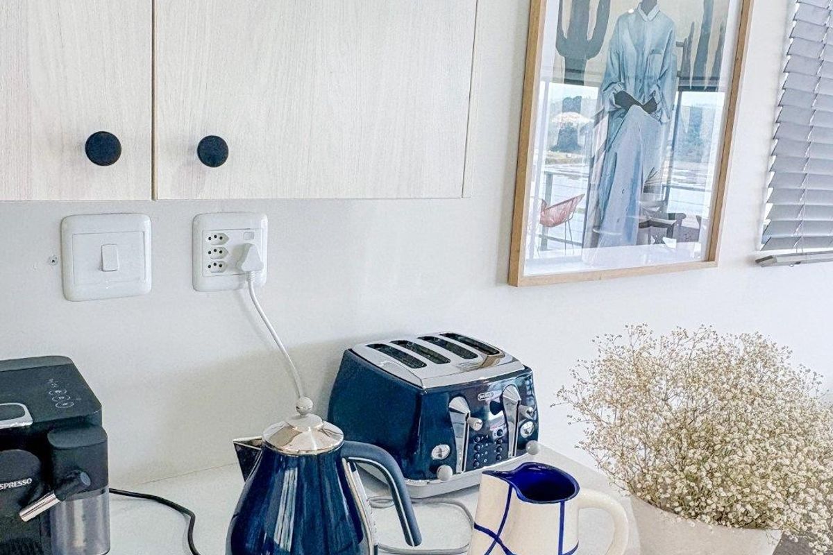 A clean kitchen workspace featuring light-toned cabinetry, a smooth countertop, and functional electrical outlets.