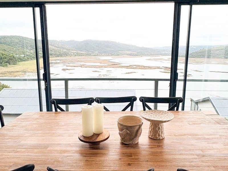 Dining area featuring large sliding glass doors that open to a balcony with expansive water and landscape views.