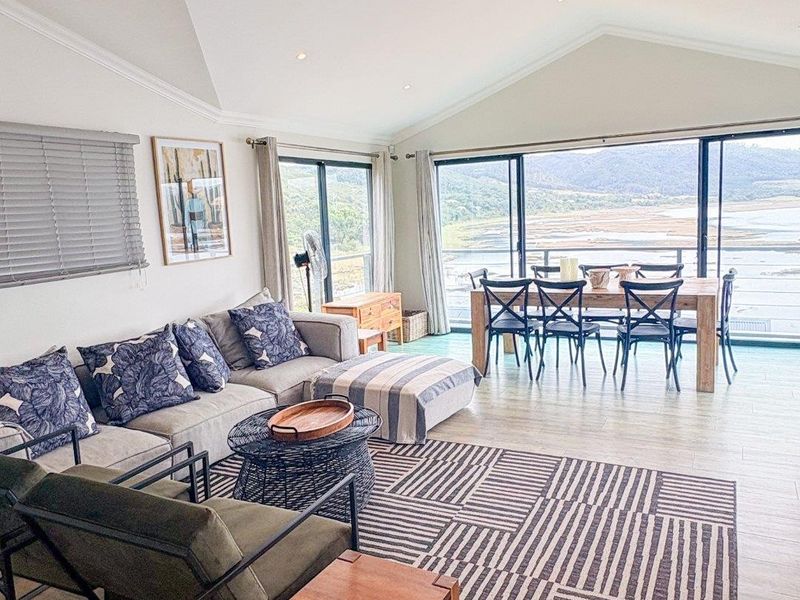 Spacious open-plan living and dining area featuring a vaulted ceiling, recessed lighting, and large sliding glass doors that offer expansive views.