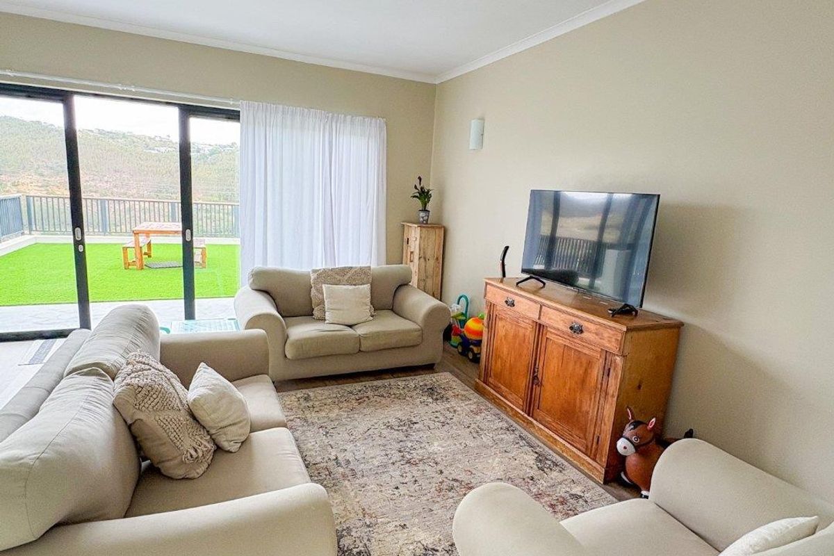 A bright living room featuring laminate flooring and large sliding glass doors that provide direct access to an outdoor patio area.