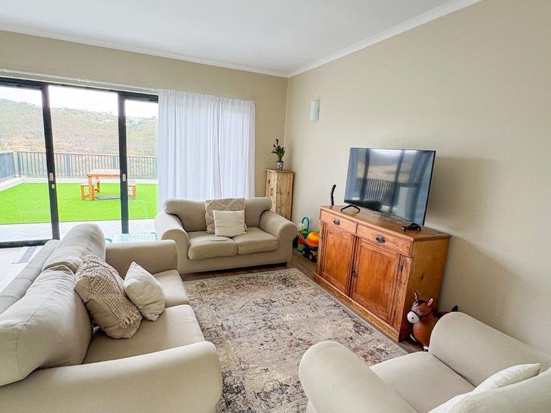 A bright living room featuring laminate flooring and large sliding glass doors that provide direct access to an outdoor patio area.