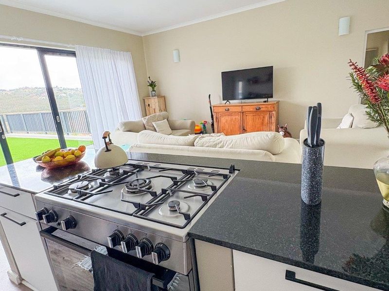 Open plan kitchen and living area featuring a modern gas stove, granite countertops, and large sliding doors leading to an outdoor space.