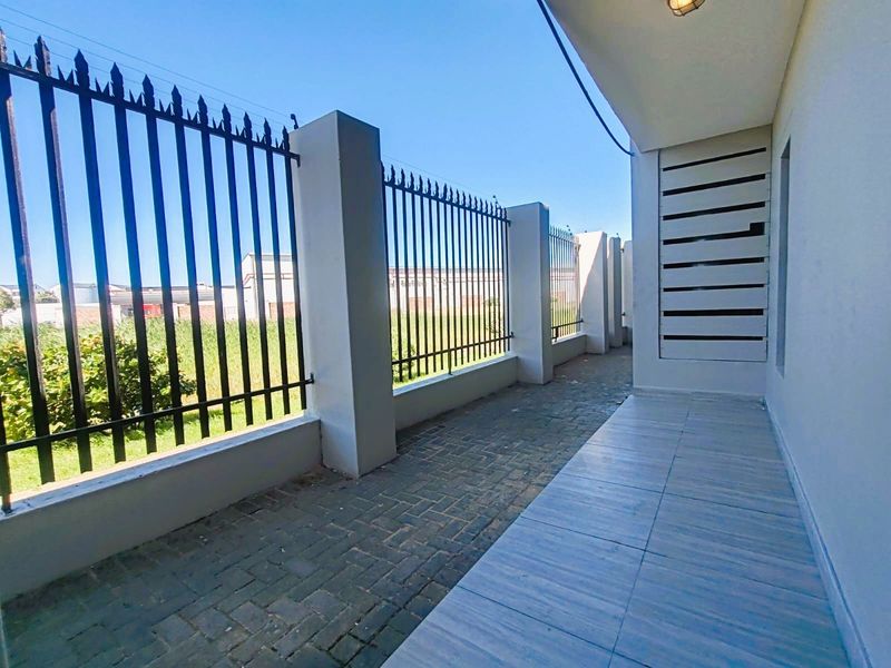 A clean, paved outdoor patio area featuring secure metal fencing, concrete pillars, and a privacy screen, offering a functional and well-maintained exterior space.