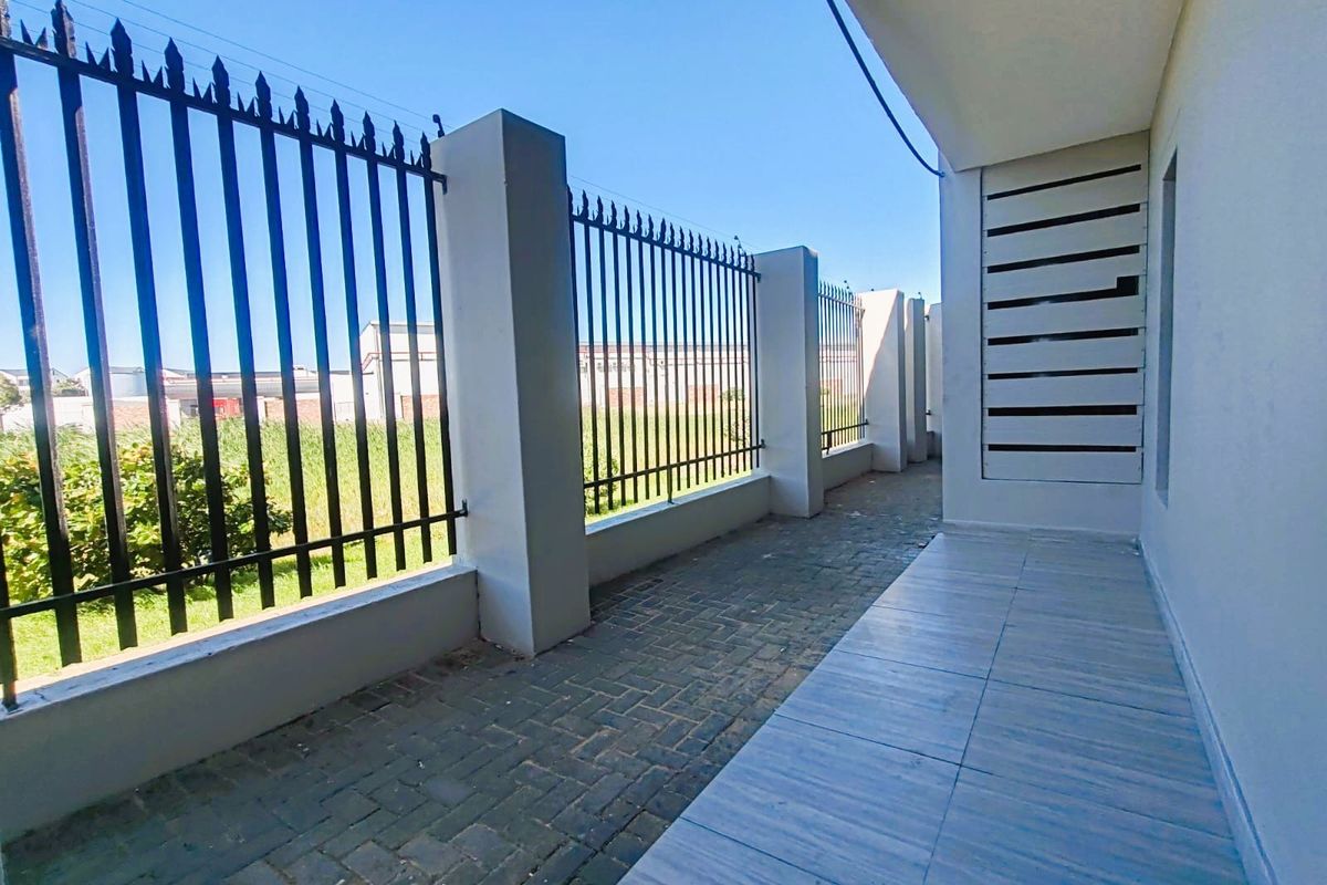 A clean, paved outdoor patio area featuring secure metal fencing, concrete pillars, and a privacy screen, offering a functional and well-maintained exterior space.