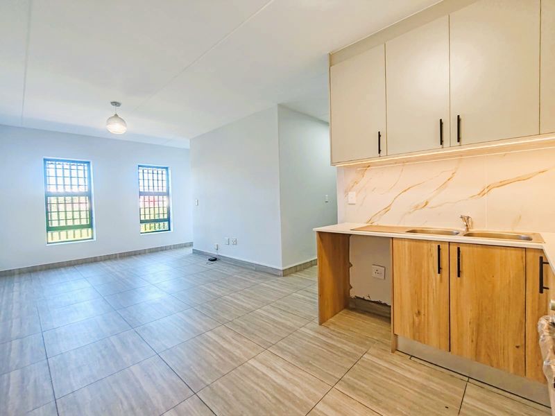 Modern open-plan living area featuring a contemporary kitchen with wood-finish cabinetry, marble-look splashback, and tiled flooring throughout.