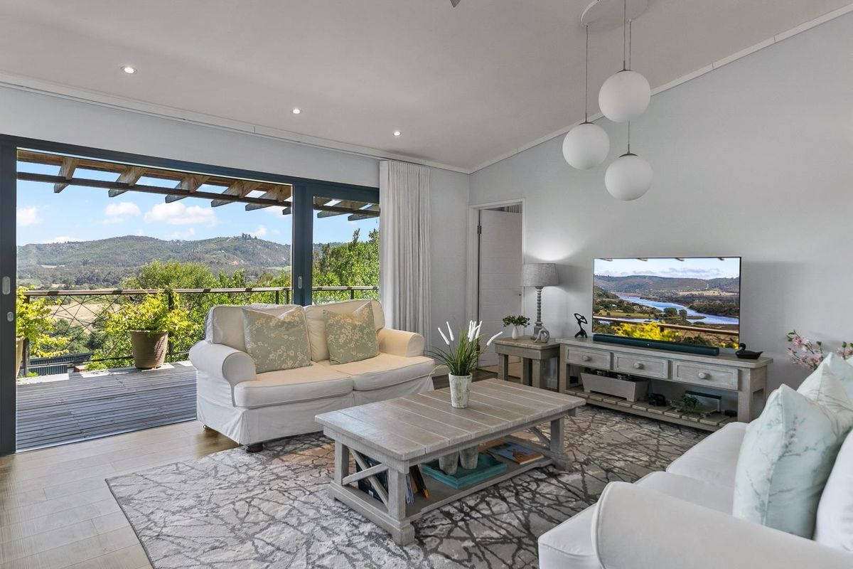 Bright living room featuring hardwood floors, recessed lighting, and large sliding doors opening onto a timber deck with scenic mountain views.
