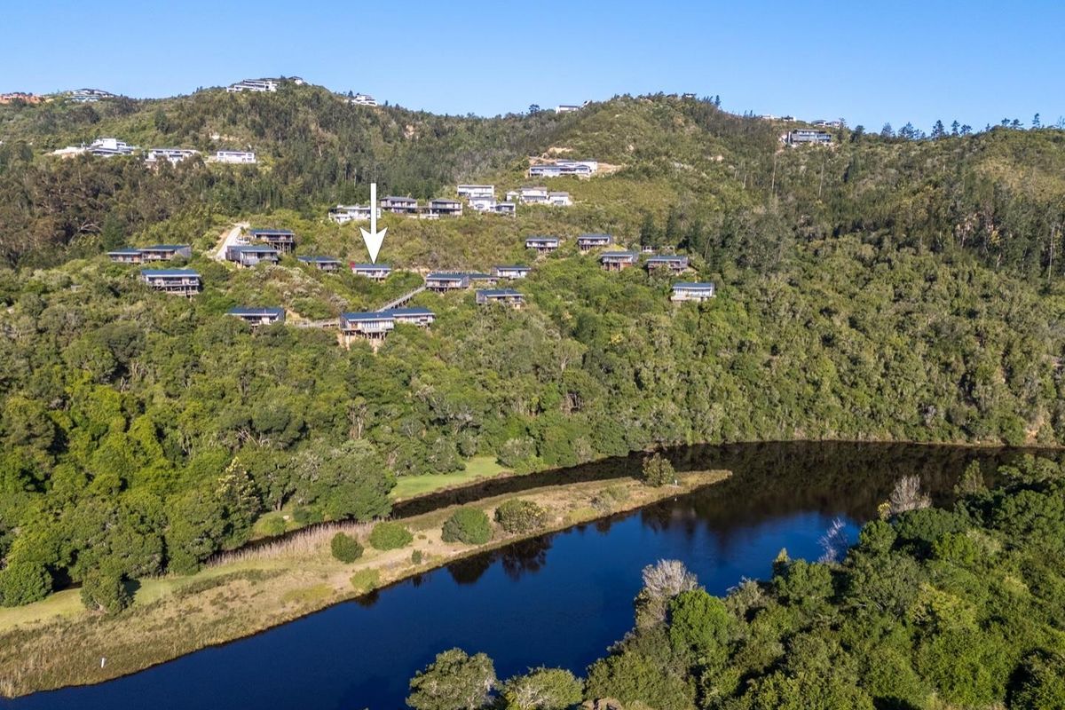 Aerial view of a hillside residential estate nestled in a lush, forested landscape overlooking a river.