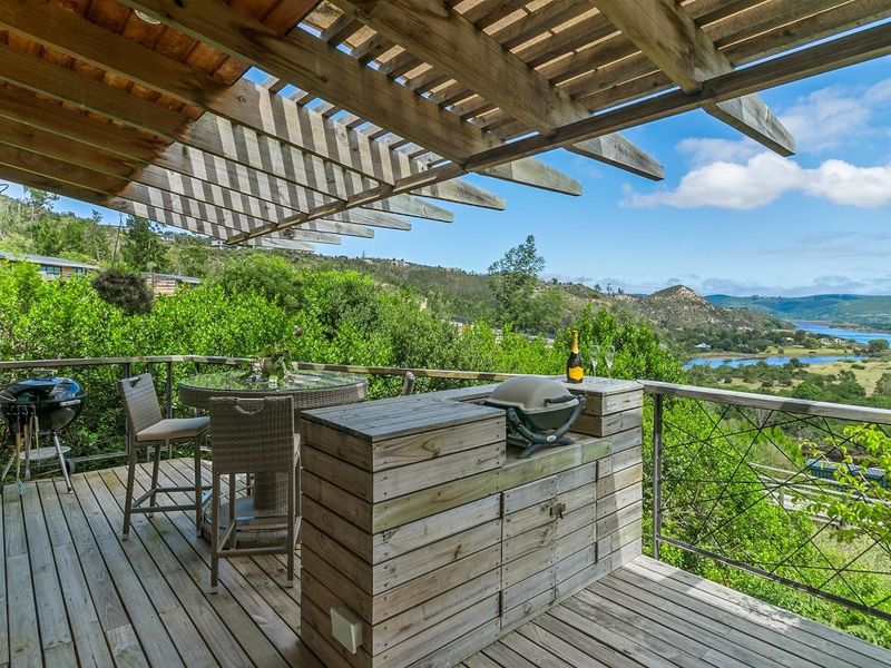 Elevated timber deck featuring a pergola, built-in cabinetry, and metal balustrade, offering expansive scenic views of the surrounding landscape and water.