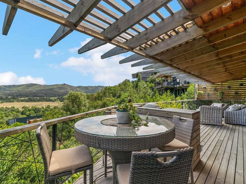 Spacious timber deck featuring a pergola, built-in counter, and expansive elevated views of the surrounding landscape.