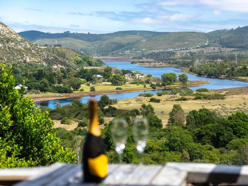 A scenic elevated view overlooking a winding river, lush green valley, and distant rolling hills.