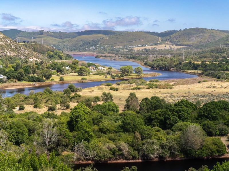 A scenic elevated view overlooking a winding river, lush green vegetation, and rolling hills in the distance.