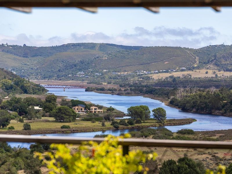 Scenic elevated view overlooking a river, surrounding landscape, and distant hills, framed by a balcony railing.