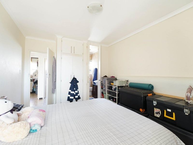 A bedroom featuring built-in cupboards and direct access to an en-suite bathroom, offering a functional layout with neutral finishes.