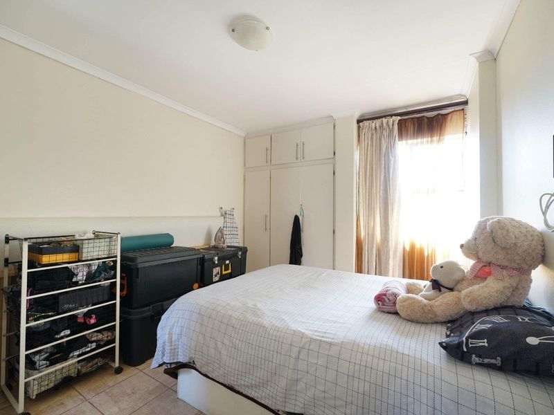A functional bedroom featuring built-in cupboards, tiled flooring, and natural light from the window.