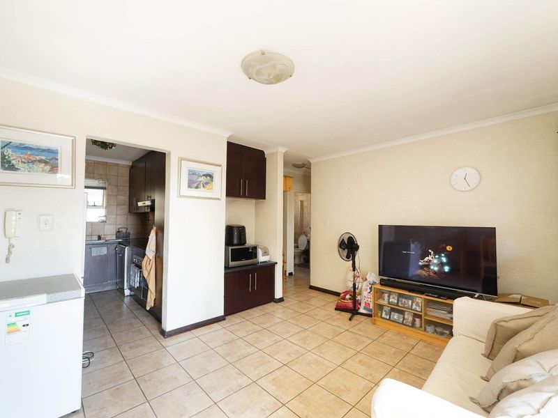 Open plan living area featuring tiled flooring and direct access to a compact kitchen space with built-in cabinetry.