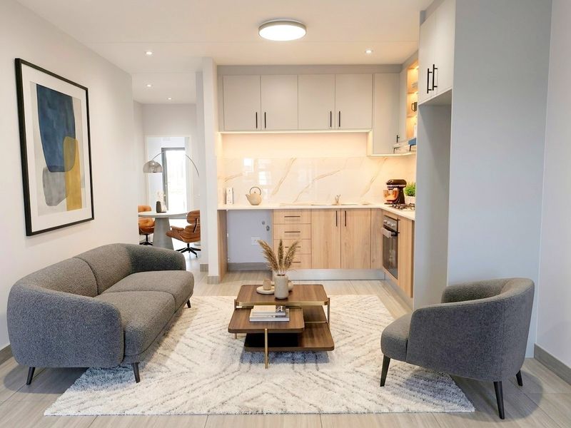 Modern open-plan living area featuring a contemporary kitchen with light wood cabinetry, marble-look splashback, and integrated appliances, seamlessly flowing into the lounge space.