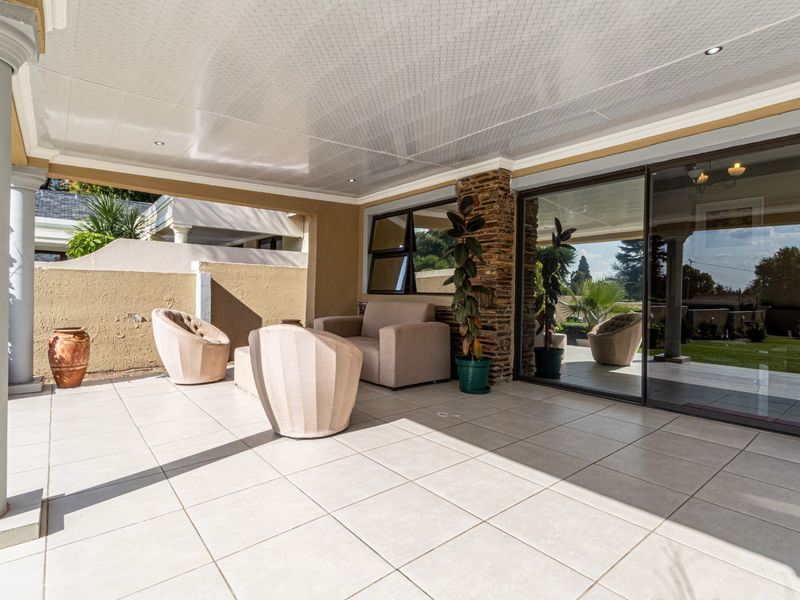 A spacious covered patio featuring tiled flooring, recessed lighting, and large sliding glass doors, providing a seamless transition to the outdoor living area.