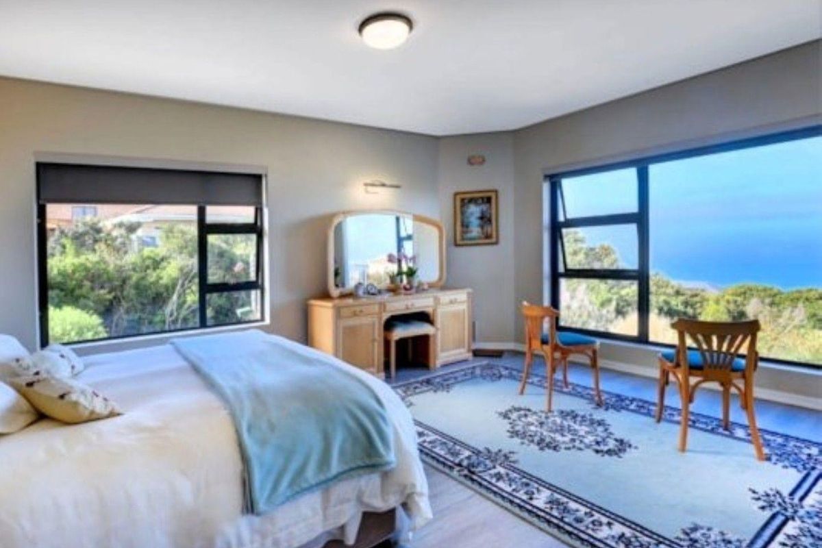 Spacious bedroom featuring large windows with scenic views, neutral wall tones, and durable laminate flooring, offering a bright and comfortable living space.