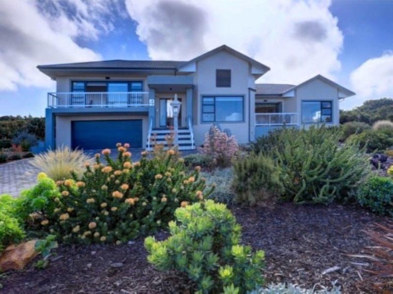 A well-maintained double-story residential property featuring a paved driveway, landscaped front garden, and an upper-level balcony.