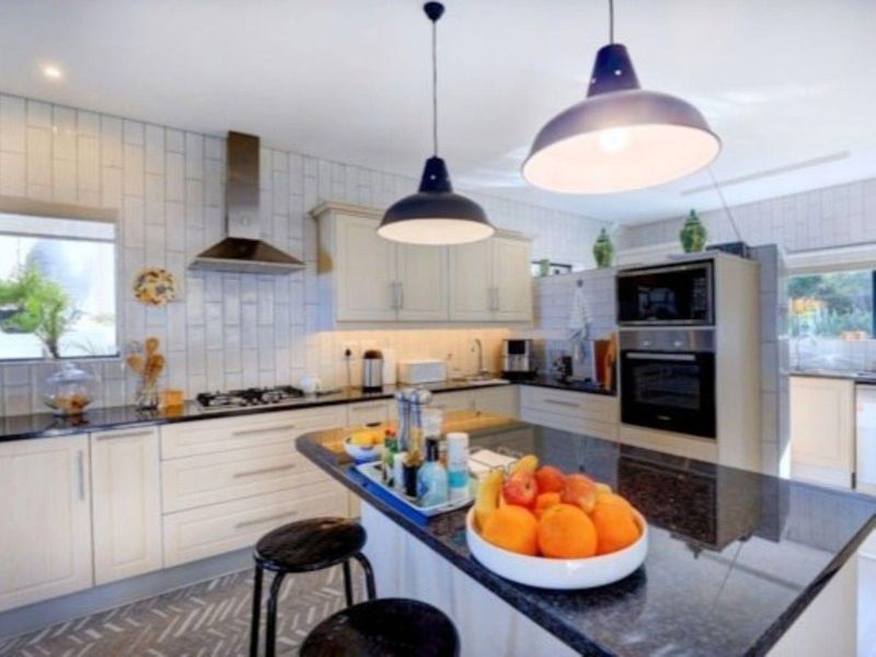 Modern kitchen featuring granite countertops, a central island, built-in oven and microwave, gas hob, and stylish subway tile backsplash.