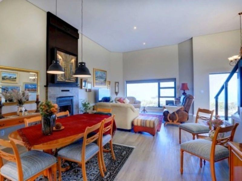 Spacious open-plan living and dining area featuring a prominent fireplace, high ceilings, and large windows with natural light.