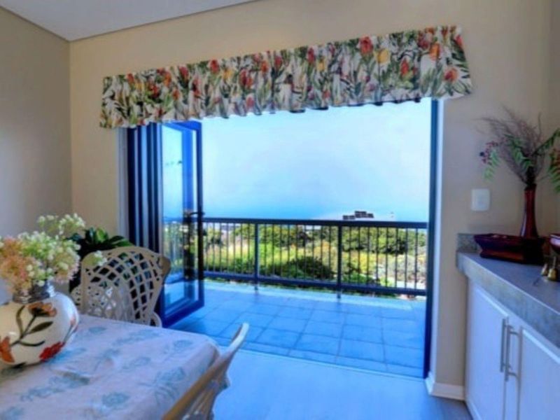 A covered balcony featuring tiled flooring and a metal balustrade, offering an open view through folding glass doors.