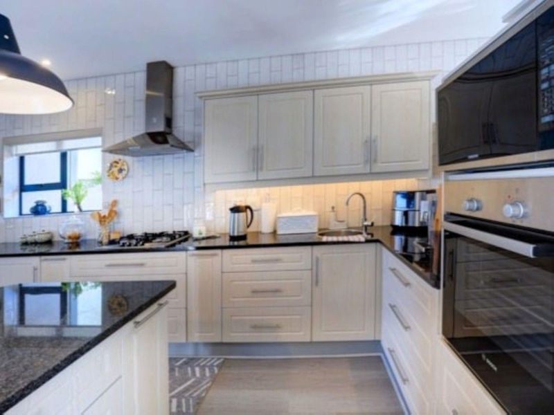 Modern kitchen featuring light-toned cabinetry, granite countertops, subway tile backsplash, and high-quality built-in appliances including a gas hob and oven.