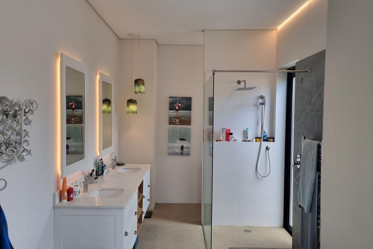 Modern bathroom featuring a double vanity with undermount sinks, a spacious walk-in shower with glass screen, and a contemporary freestanding bathtub.