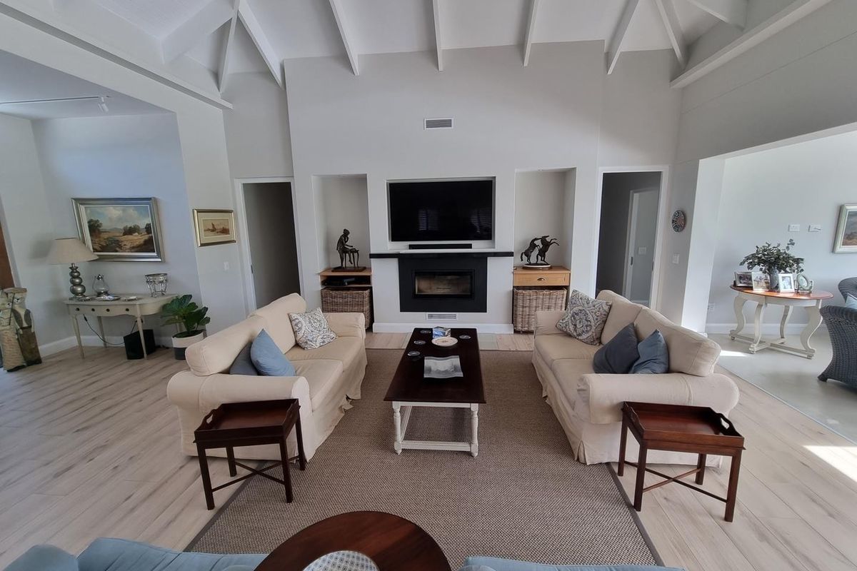Spacious living room featuring a high vaulted ceiling with exposed rafters, a central built-in fireplace, and recessed shelving units.