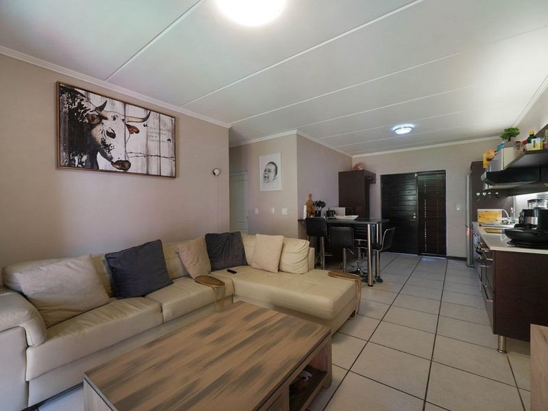 Open plan living area featuring tiled flooring, a functional kitchen with built-in cabinetry, and a breakfast bar, creating a versatile living and dining space.