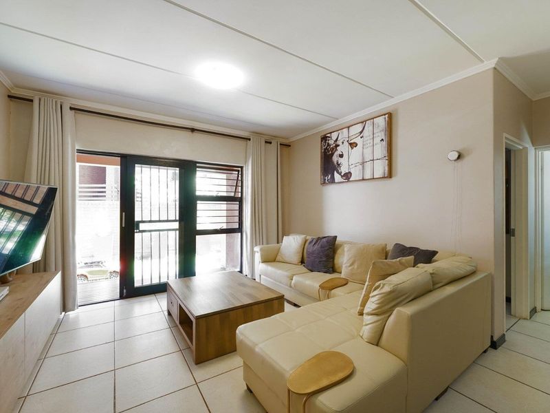 A living room featuring tiled flooring and a sliding glass door with a security gate, providing access to the outdoor area.