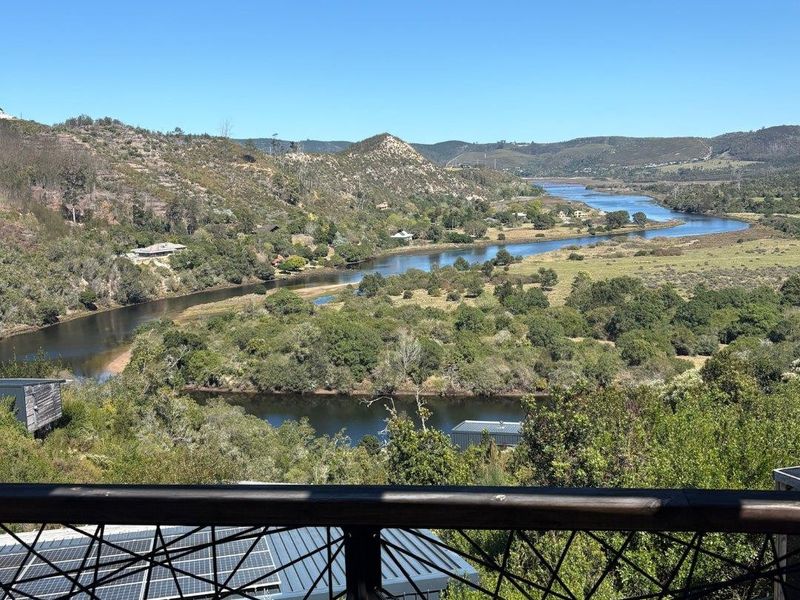 Elevated view overlooking a scenic river, valley, and natural landscape, captured from a balcony with a decorative metal balustrade.