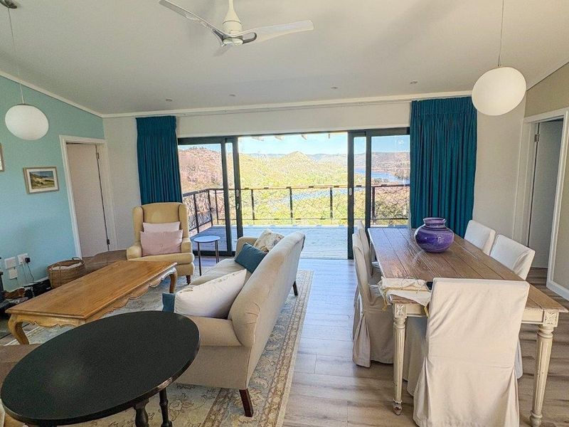 Spacious open-plan living and dining area featuring modern laminate flooring, ceiling fan, and large sliding doors opening to a scenic outdoor balcony.