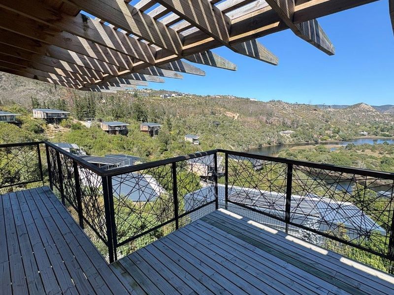 Spacious elevated balcony featuring timber decking, a wooden pergola, and decorative metal balustrades, offering expansive views of the surrounding landscape and river.