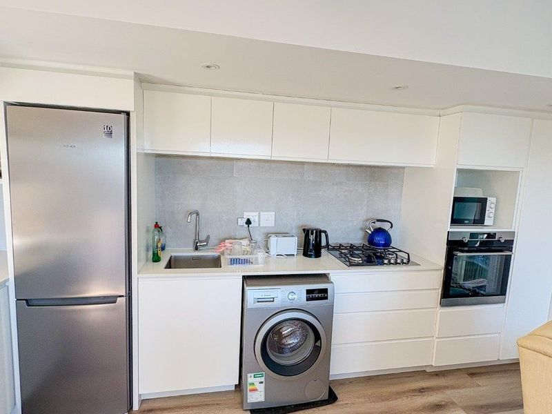 Modern kitchen featuring white cabinetry, stainless steel appliances, gas cooktop, built-in oven, and clerestory windows providing natural light.