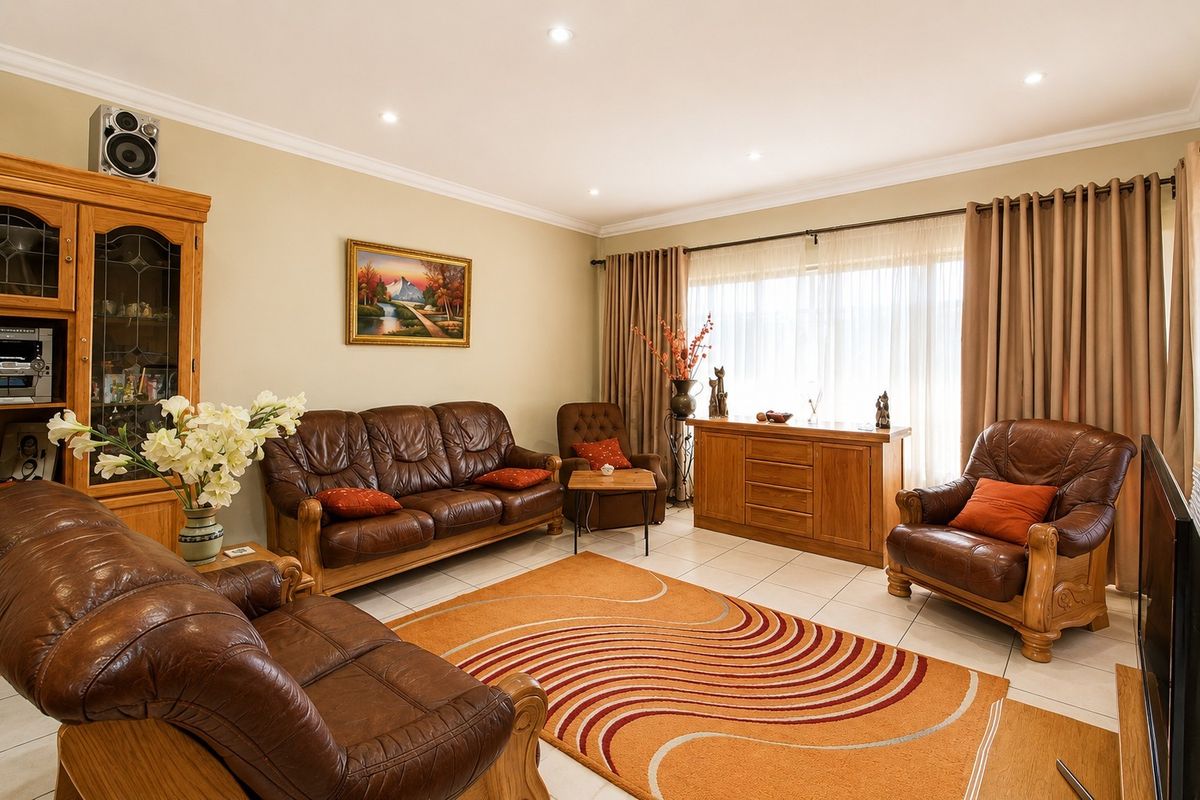 A well-maintained living room featuring tiled flooring, recessed downlighting, and decorative ceiling cornicing, providing a comfortable and functional space.
