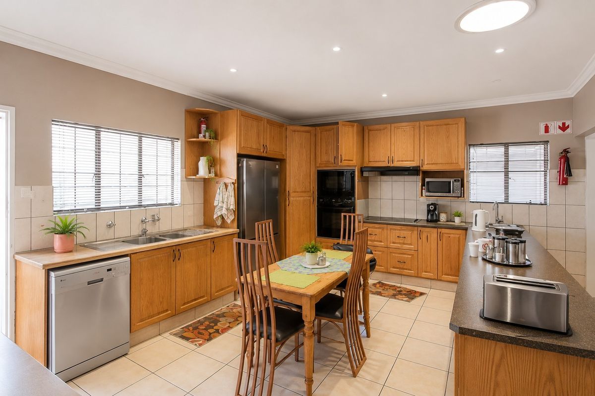 Spacious kitchen featuring wooden cabinetry, laminate countertops, double basin sink, built-in oven, and tiled flooring with an integrated dining area.