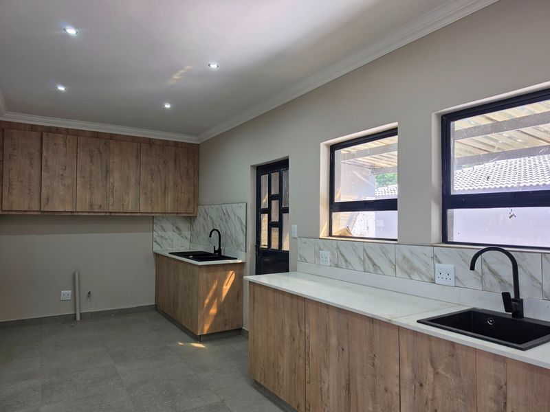 Modern kitchen featuring wood-look cabinetry, marble-effect backsplash, stone countertops, and black fixtures, offering a clean and contemporary aesthetic.
