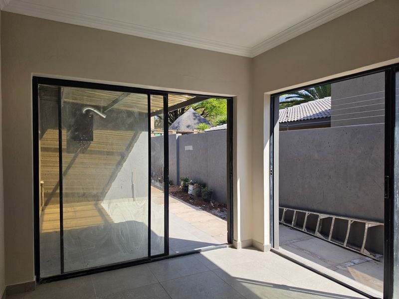 An empty living area featuring large sliding glass doors that provide direct access to the outdoor patio and garden space.