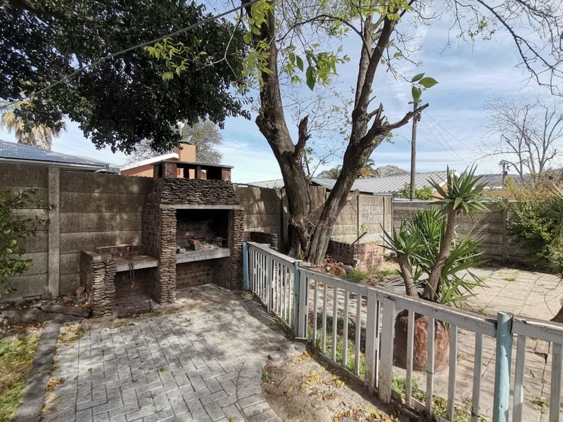 Outdoor patio area featuring a built-in brick braai, paved flooring, and perimeter fencing, offering a functional space for outdoor entertaining.