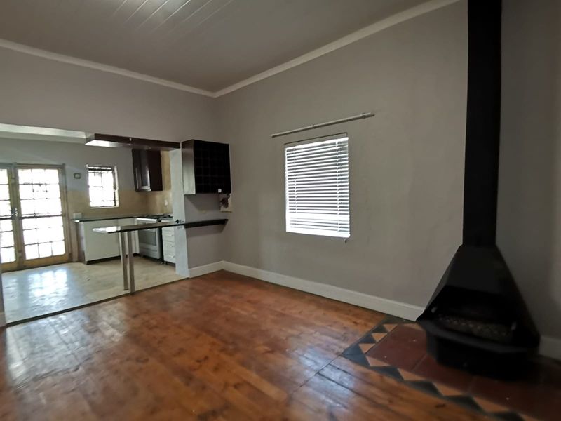 Open plan living area featuring hardwood floors, a modern freestanding fireplace, and an adjoining kitchen with breakfast bar and built-in cabinetry.