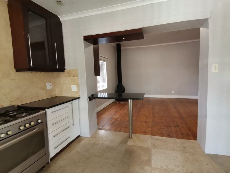 Open plan kitchen and living area featuring a breakfast bar, gas stove, stone tile and hardwood flooring, and a central fireplace.