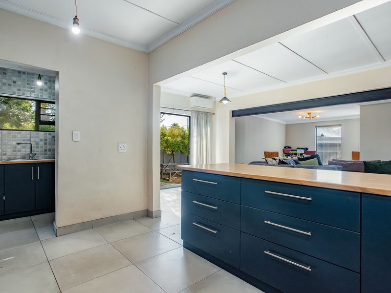 An open-plan living area featuring a modern kitchen island with dark cabinetry, tiled flooring, and seamless flow to the outdoor patio area.