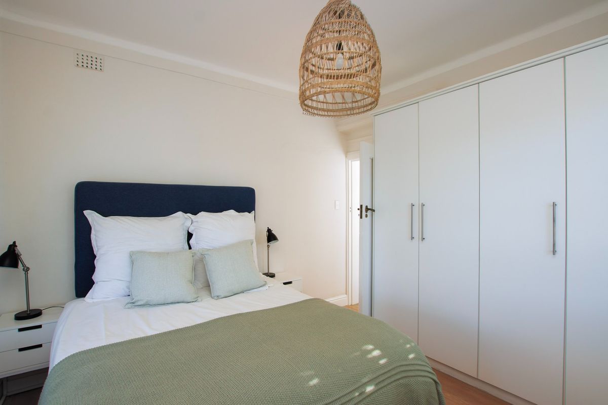 A well-maintained bedroom featuring neutral walls, timber flooring, and a large built-in wardrobe providing ample storage space.